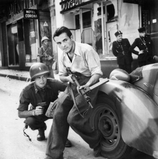 American officer and French partisan crouch behind an auto during a street fight, France, U.S. Army
