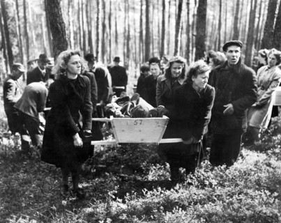 Civilians bearing victims of SS killings to burial ground, after bodies were exhumed from mass