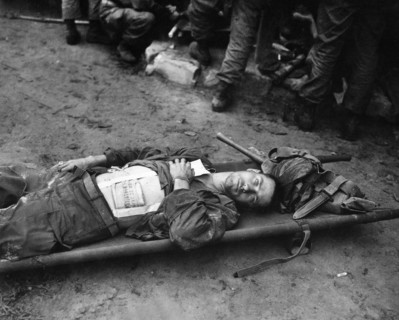 Private First Class, Thomas Conlon, 21st Infantry Regiment, laying on stretcher at medical aid