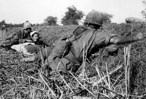 American soldier of 1st Infantry Division motioning to woman refugee to keep her children's heads