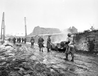 American Infantrymen of 290th Regiment, 75th Division, moving along road hit by Nazi mortars, jeep