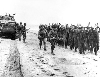 American soldiers marching group of German prisoners along beachhead after which they will be sent