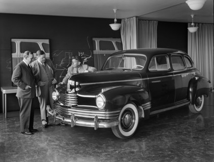 Norman Bel Geddes and Nash-Kelvinator corporation officials inspecting a marked-up model of a new