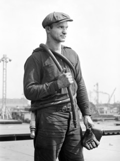 Factory worker carrying rubber hose, Bethlehem-Fairfield shipyards, Baltimore, Maryland, USA,