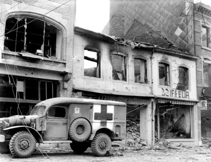 American ambulance waiting outside bombed building while a searcher looks for persons injured