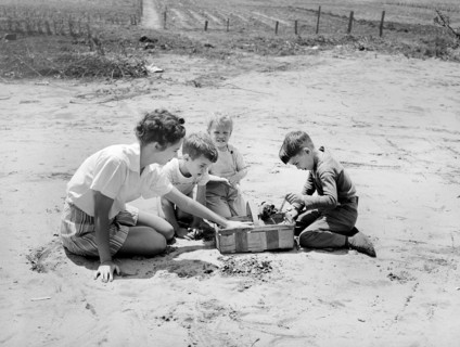 Woman and three children playing with puppy in basket, Point Pleasant, West Virginia, USA, Arthur S