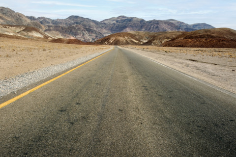 Asphalt road with mountains in background, diminishing perspective, Death Valley National Park,
