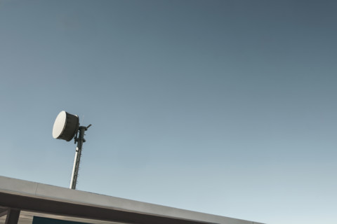 Microwave transmitter mounted to the roof against blue sky