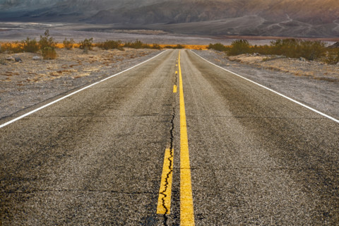 Two-lane asphalt road with mountains in background, diminishing perspective, Death Valley National