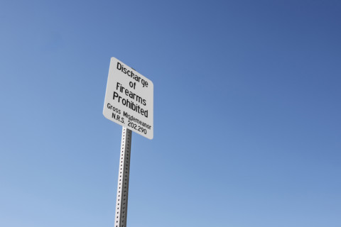 Discharge of Firearms Prohibited' warning sign, low angle view against blue skey,