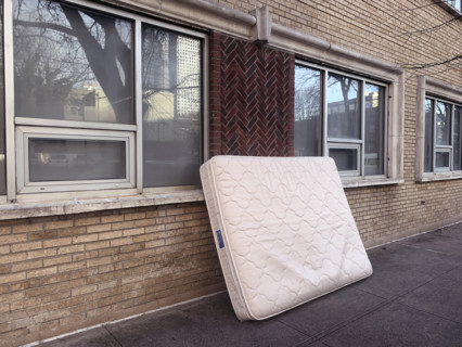 Discarded mattress leaning against building on sidewalk, Brooklyn, New York, USA