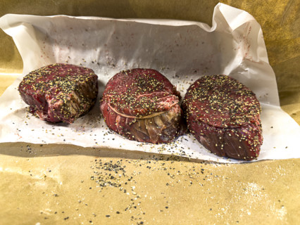 three cuts of raw filet mignon seasoned with herbs