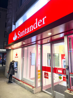 Santander retail bank office, woman using outdoor ATM machine at night, New York City, New York,