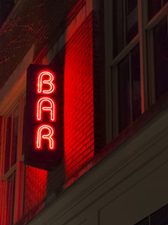 Neon red bar sign on building exterior at night, New York City, New York, USA