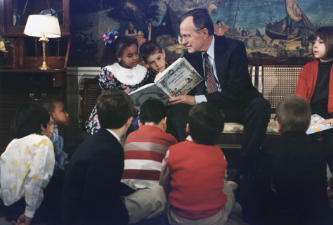 U.S. President George H.W. Bush reading a book to children during Great American Read Aloud Day,