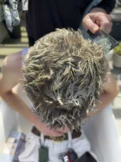 High angle view of young adult man getting his hair bleached
