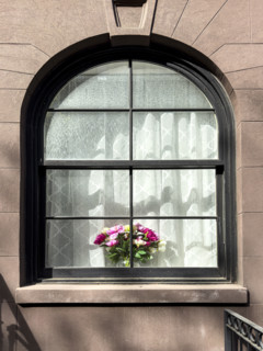 Flower arrangement on sill of residentail apartment's arched window, New York City