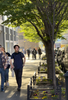 Group of people walking along shaded sidewalk, New York City