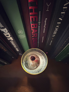 High angle view of whiskey sour cocktail against a row of cocktail recipe books