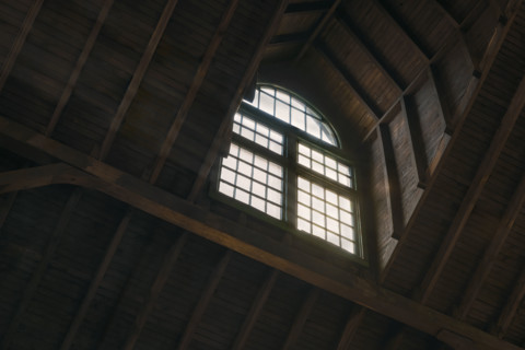 Low angle view of daylight coming through arched window in old wood-framed building