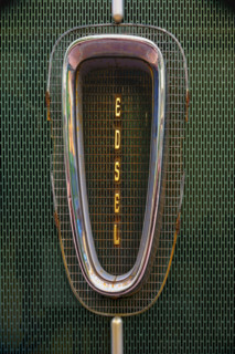 Antique rusted Ford Edsel car grille against green metal background
