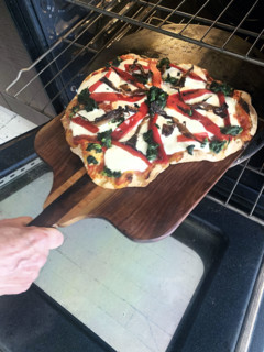 Homemade pizza being put in oven