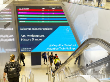 LIRR digital departure board above escalator and stairs, Moynihan Train Hall, Pennsylvania Station,