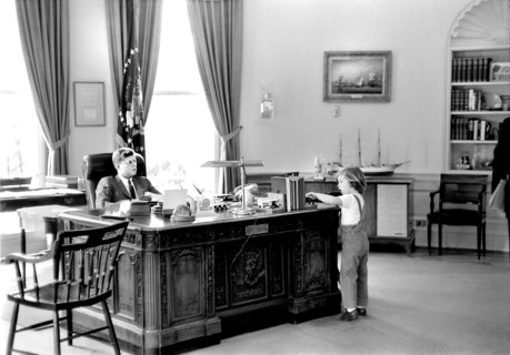U.S. President John F. Kennedy sitting at his desk while his daughter, Caroline Kennedy, visits the