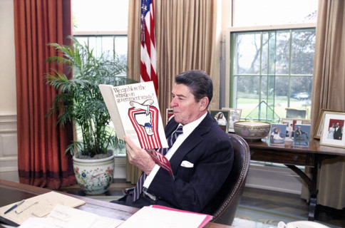 U.S. President Ronald Reagan reading a book "We can blow the whistle on Government waste" in the