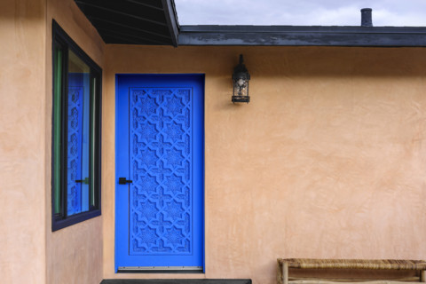 Blue carved wood door on stucco house