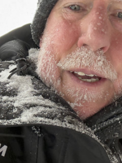 Head and shoulders portrait of mature adult man with face covered in snow and ice