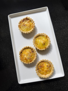 High angle view of four mini ham and cheese tarts on rectangular white plate