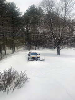 White pickup truck with plow attachment removing snow from residential driveway