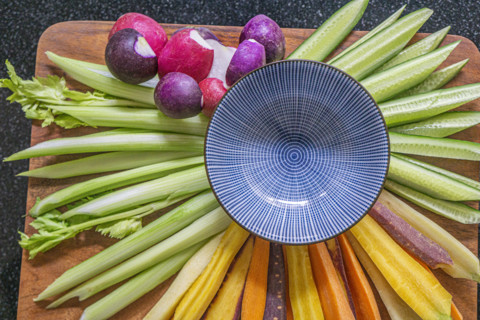 High angle view of fresh cut vegetables with blue bowl on wood board