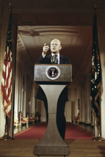 U.S. President Gerald R. Ford standing at lectern during first press conference, White House East