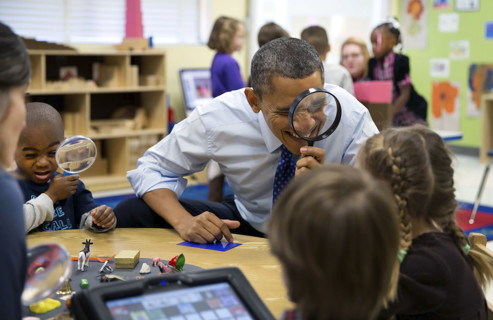 U.S. President Barack Obama playing magnifying glass game with children during a visit to a