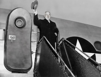 President Harry S. Truman waving his hat from door of his airplane, "Sacred Cow" as he prepares to