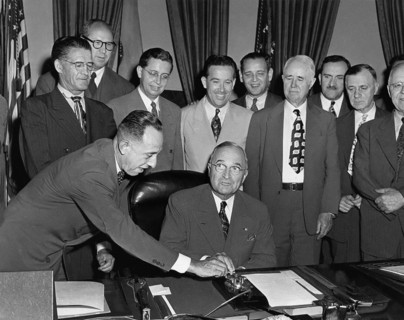 U.S. President Harry S. Truman seated at his desk preparing to push button activating a new