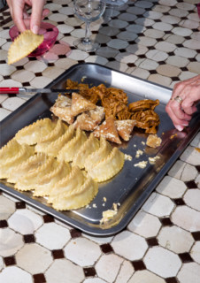Woman's hands reaching toward tray filled with traditional pastries