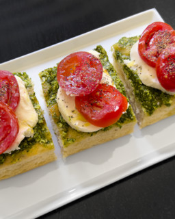 Tomato, mozzarella, basil and pesto and toasted bread on white plate