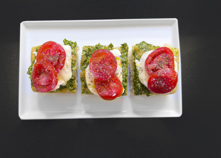 Tomato, mozzarella, basil and pesto and toasted bread on white plate