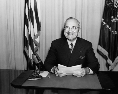 U.S. President Harry S. Truman smiling for photographers while delivering radio speech to the