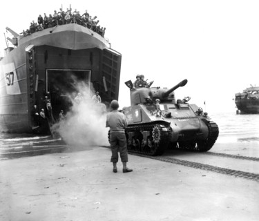 Sherman tanks, manned by French armored troops, rolling out from landing ship ramp onto Utah beach,