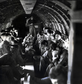 Nurse with wounded American soldiers on C-47 airplane crossing English Channel from Normandy,