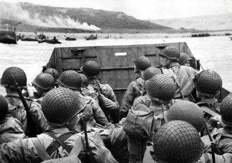 American assault troops in landing craft huddling behind protective front of craft as it nears