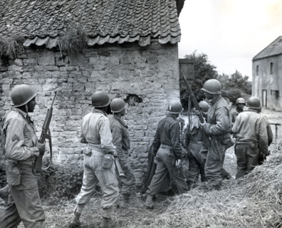 Platoon of Negro troops surrounding farmhouse as they prepare to eliminate a German sniper holding