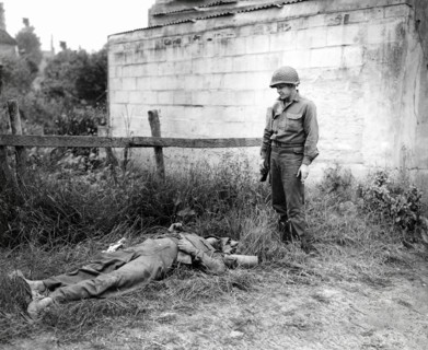 U.S. Sergeant Joseph C. Self of Harriman, Tennessee, looking over dead German sniper, Omaha