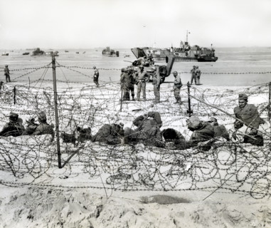 German prisoners resting in barb-wired enclosure after being interrogated by American soldiers,