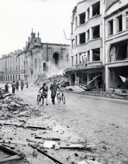 Residents move past bombed buildings hit by German Luftwaffe in an attempt to destroy bridge over