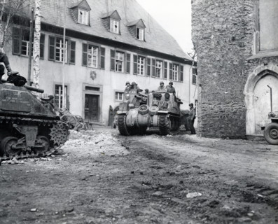 Tank of U.S. 9th Armored Division, U.S. First Army, rolling through street of Limburg, Hesse,